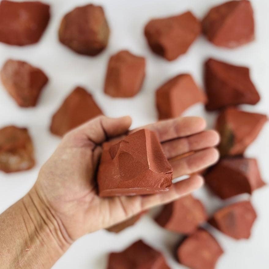 Hand holding a rough stone from the Chakra Rough Stone Crystal Set of 7 - Boxed Collection, perfect for energy healing.