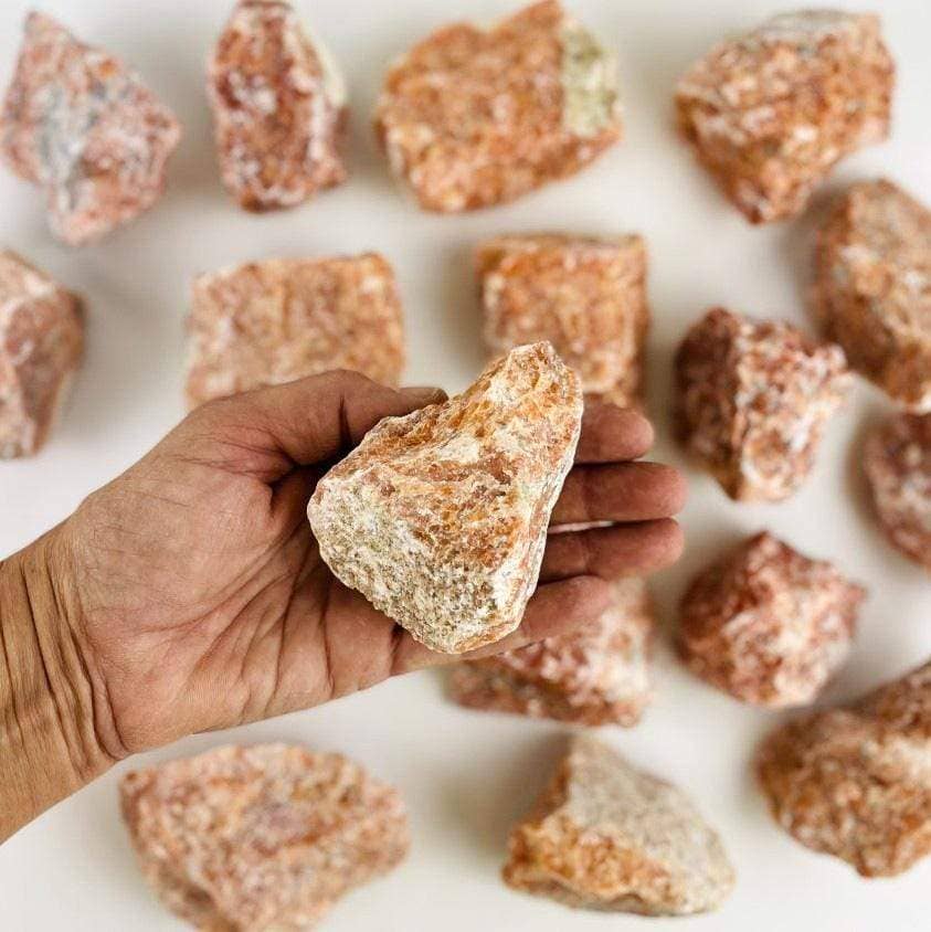 Hand holding a rough stone from the Chakra Rough Stone Crystal Set of 7 - Boxed Collection for energy balance.