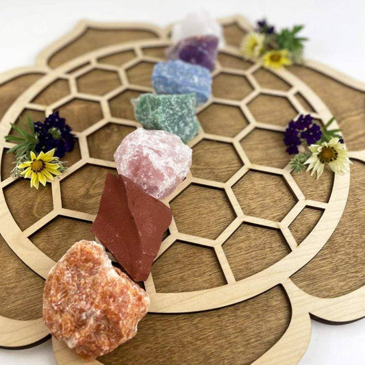 Chakra Rough Stone Crystal Set of 7 - Boxed Collection displayed on a wooden surface with flowers for energy balance.