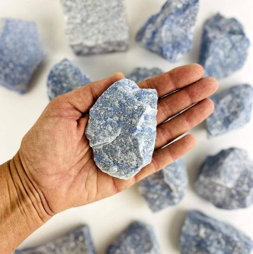 Hand holding a rough blue crystal from the Chakra Rough Stone Crystal Set of 7 - Boxed Collection for energy balance.