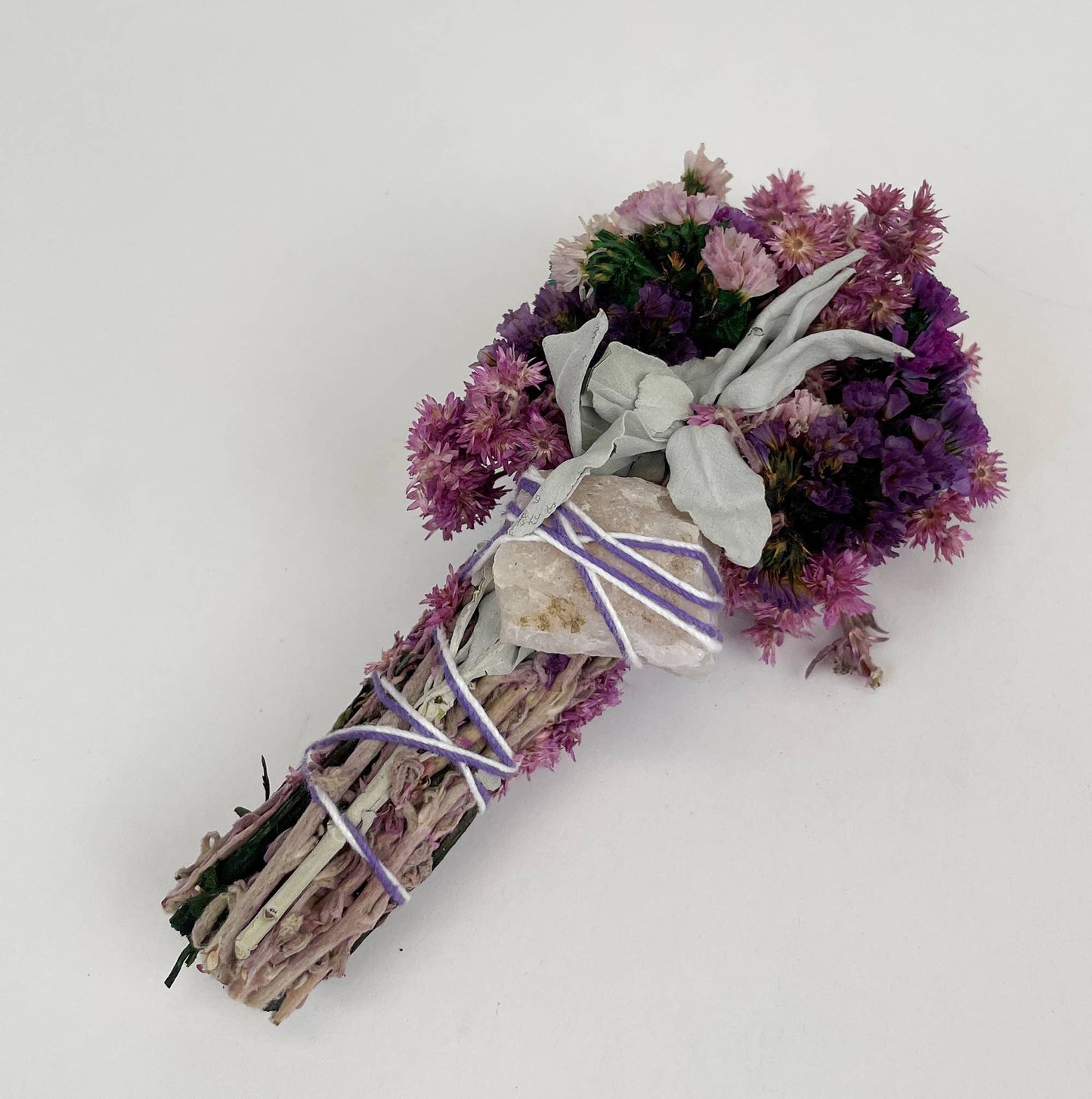 6" Pink smudge wand featuring vibrant flowers, sage, and rose quartz crystal for magical cleansing. Perfect for rituals.