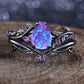 Ornate ring with a purple opal stone on a wooden surface